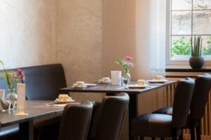 Heller Frühstücksraum mit Tischen.